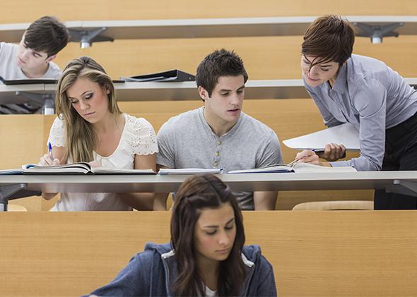 Teacher helping students in lecture hall